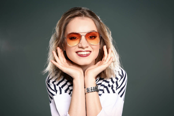 Beautiful young woman with sunglasses posing on color background - Foto, Imagem