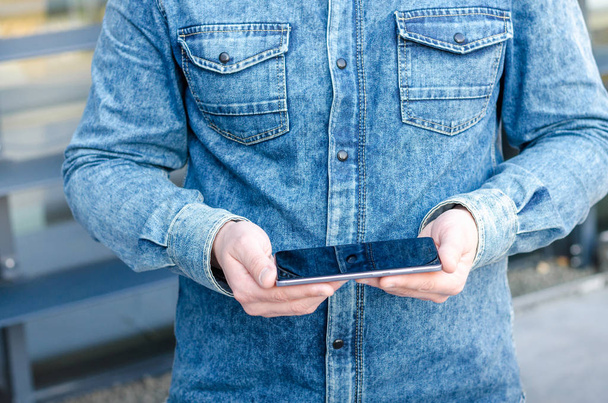 Yakın kadar Hipster iş adamı kullanarak akıllı cep telefonu App açık siyah Oled ekran arka plan Denim Jeans Gömlek şık giyinmiş - Fotoğraf, Görsel