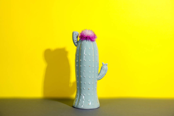 Trendy cactus shaped ceramic vase with flower on table against color background - Fotografie, Obrázek