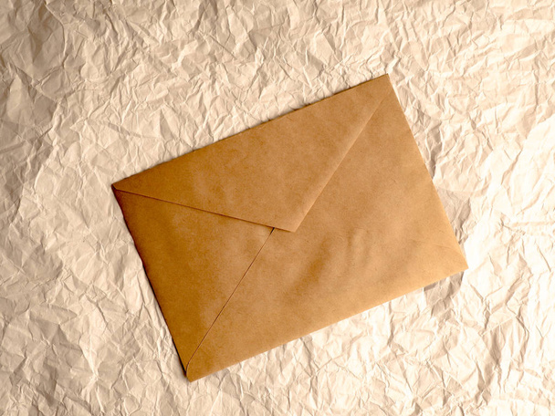envelop van Kraft papier ligt op verfrommeld papier - Foto, afbeelding