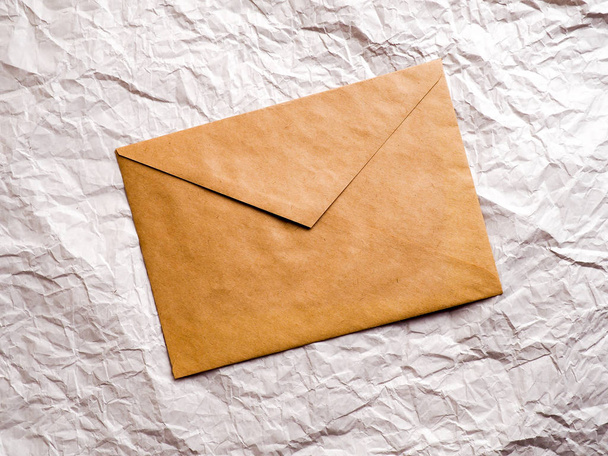 Umschlag mit Kraftpapier liegt auf zerknülltem Papier - Foto, Bild