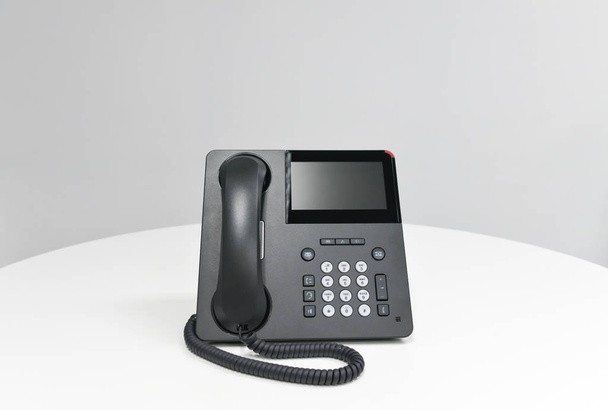 Téléphone IP noir, téléphone de bureau sur la table blanche dans la salle de réunion
 - Photo, image