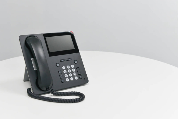 Telefono IP nero, telefono ufficio sul tavolo bianco nella sala riunioni
 - Foto, immagini