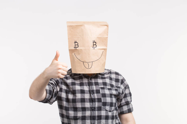 Άντρες φορώντας αστεία χαρτί μάσκα με τον αντίχειρα επάνω και σύμβολο του bitcoin - Φωτογραφία, εικόνα