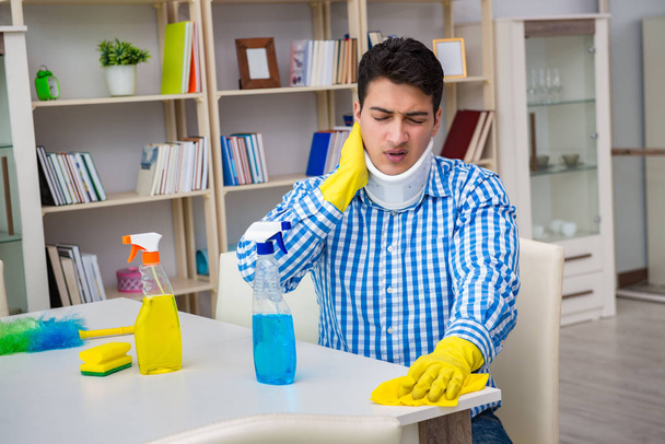 Mężczyzna z urazami szyi sprzątanie domu w koncepcji sprzątania - Zdjęcie, obraz