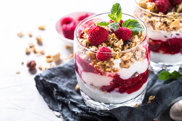 Yogurt parfafait with granola and raspberries in glass. - Valokuva, kuva