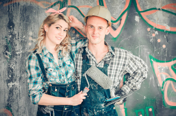 Portret młodego mężczyzny i kobiety w kombinezon z narzędzia do naprawy wnętrza w ręce. Pojęcie, budowa i remont domu. - Zdjęcie, obraz