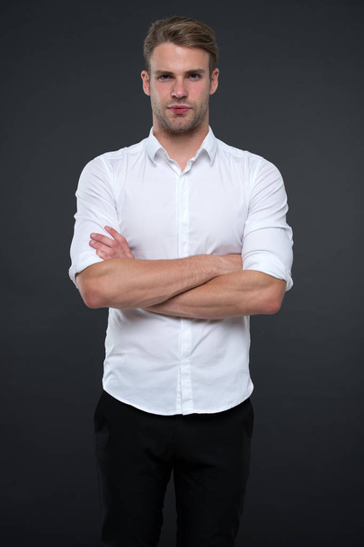 I am here to help you. Man shop consultant looks confident and hospitable. Man calm face posing confidently with folded arms grey background. Guy with bristle ready to help you in shop - Foto, Imagen