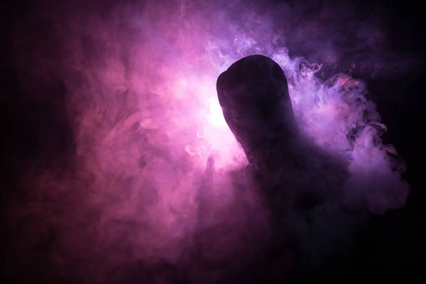 Dampfender Mann mit einem Mod. eine Dampfwolke. dunkler nebelverhangener Hintergrund aus Rauchwolken. Das Verdampfen einer elektronischen Zigarette mit viel Rauch. vape Konzept. Selektiver Fokus - Foto, Bild