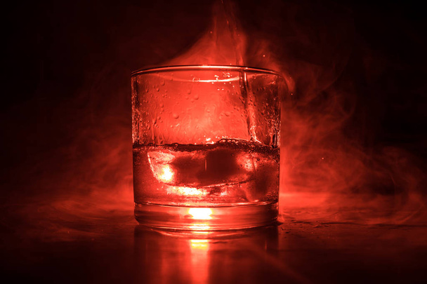 Bardak viski ve buz ile renk ışık ahşap yüzeyde ve sis arka plan üzerinde. Yakın çekim. Reklam atış - Fotoğraf, Görsel