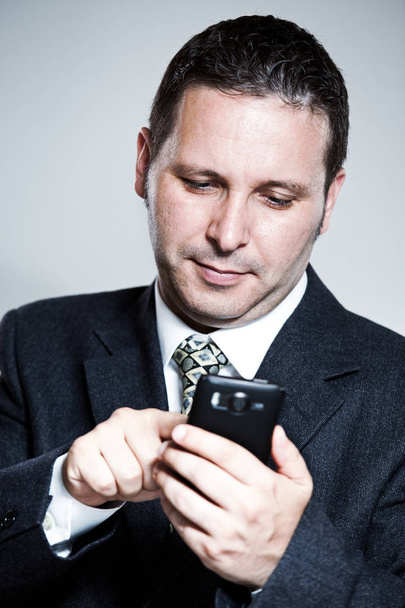 κείμενα νεαρός επιχειρηματίας για ένα κινητό τηλέφωνο. τετράγωνο βολή. απομονωθεί σε λευκό - Φωτογραφία, εικόνα