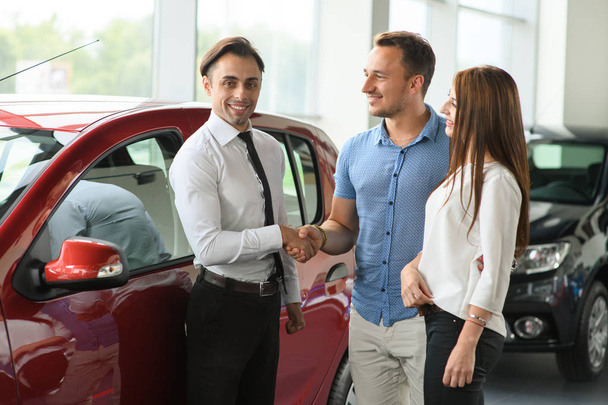 Un paio hanno comprato un'auto nuova. Venditore stringe la mano con il cliente
. - Foto, immagini