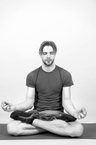 Man meditate on yoga mat. Sportsman relax in lotus pose. Fashion athlete practice yoga in gym. Meditation for body and mind health. Meditation or zen and peace concept - Photo, Image