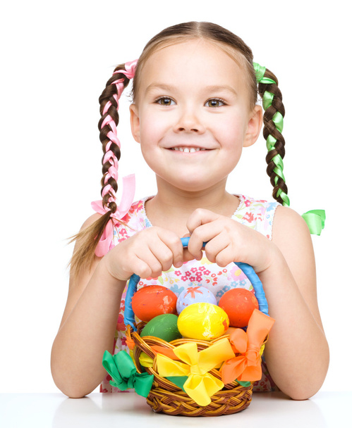 Little girl with basket full of colorful eggs - Fotó, kép