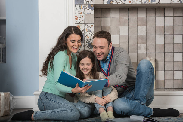Family portrait of happy parents and their daughter read together at home - Photo, Image