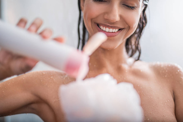 Beaming girl putting shower gel - Foto, afbeelding