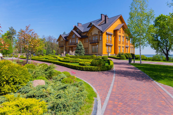 красная каменная дорожка к деревянному дому с красивым ландшафтом сада
 - Фото, изображение