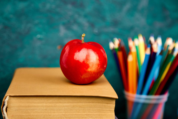 Back to school supplies. Books and red apple on green background. Still life with alarm clock. Copy space. - Photo, Image