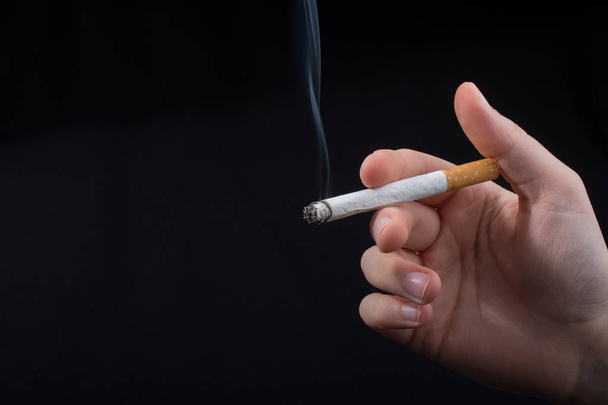 Hand is holding smoking cigarette with smoke around - Fotografie, Obrázek