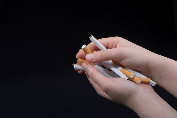 Рука випускає сигарети на чорному тлі
 - Фото, зображення