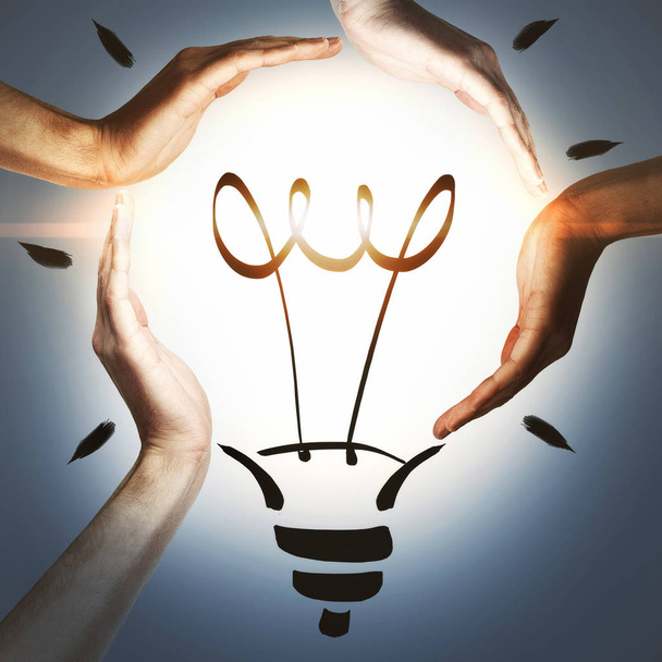 business and innovative idea concept design with 4 hands holding drawn light bulb  - Fotoğraf, Görsel