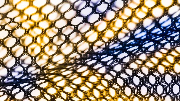 abstrakte Textur eines Netzes mit sechseckigen Zellen. künstlerisches Detail des dekorativen Netzes in schwarzer, gelber und blauer Farbe auf weißem Hintergrund. Konzept von Wissenschaft, Forschung, Technologie und Industrie. - Foto, Bild