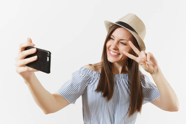 Jonge mooie vrouw gekleed blauwe jurk, hoed doen selfie geschoten op mobiele telefoon- of videogesprek geïsoleerd op een witte achtergrond. Mensen, oprechte emoties, lifestyle concept. Gebied van de reclame. Kopiëren van ruimte - Foto, afbeelding