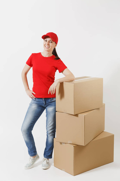 Full length portrait of delivery woman in red cap, t-shirt isolated on white background. Female courier or dealer standing near empty cardboard boxes. Receiving package. Copy space for advertisement - Photo, Image