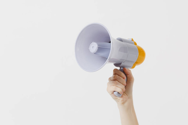 Close up female holds in hand bullhorn public address megaphone isolated on white background. Hot news, announce discounts sale, communication concept. Copy space. Advertising area - Photo, Image