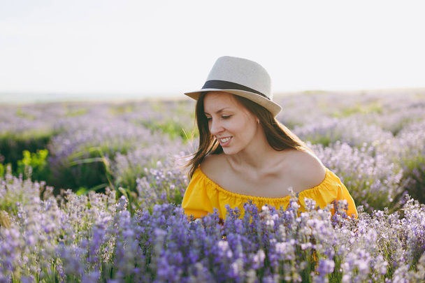 Portrait of young sensual beautiful woman in yellow dress on purple lavender flower blossom meadow field outdoors on summer nature background. Tender female near flowering bush. Lifestyle concept - Фото, зображення