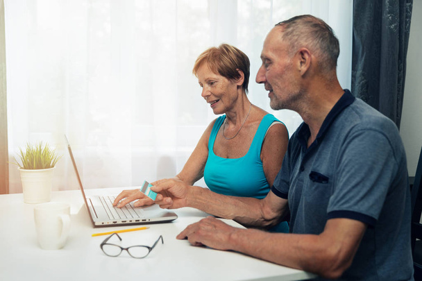 Seniorenpaar nutzt Laptop für Internet-Einkäufe und Zahlungen zu Hause - Foto, Bild