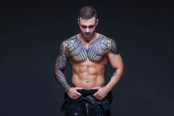 The man with a muscular naked torso with tattoos on the dark background. ABS - Foto, immagini