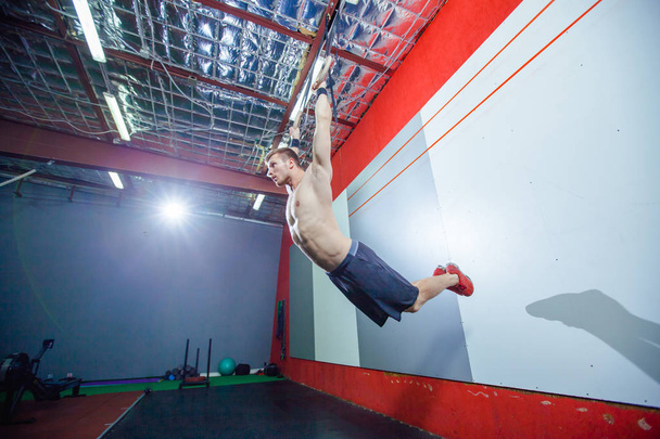 Muscle-up exercise young man doing intense cross fit workout at the gym on gymnastic rings. - Foto, Imagen
