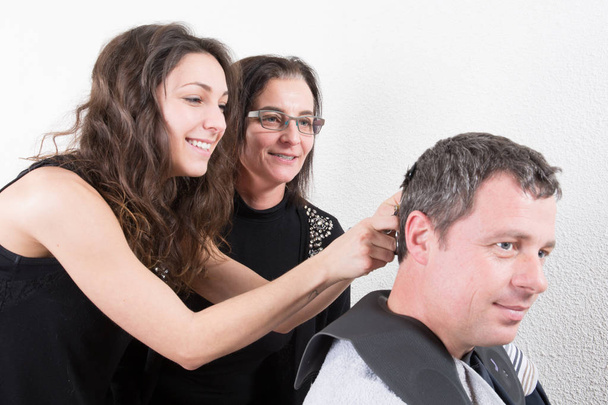 jeune étudiante en coiffure avec son professeur coupe les cheveux d'un homme
 - Photo, image