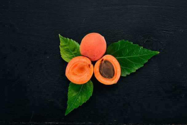 Fresh apricots with leaves On a black wooden background. Top view. Free space for your text. - Photo, image