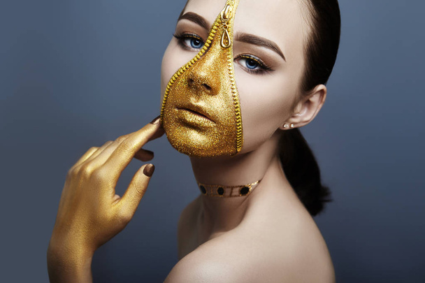 Creative grim makeup face of girl Golden color zipper clothing on skin. Fashion beauty creative cosmetics and skin care halloween. Brunette woman on dark background, beautiful big eyes and smooth skin - Foto, Bild
