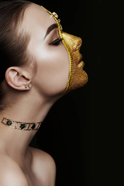 Creative grim makeup face of girl Golden color zipper clothing on skin. Fashion beauty creative cosmetics and skin care halloween. Brunette woman on dark background, beautiful big eyes and smooth skin - Photo, image