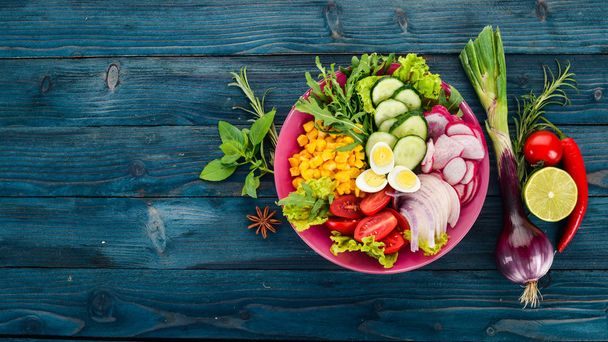 Fresh Vegetable Salad. Corn, radish, onion, cucumber, quail eggs. On a wooden background. Top view. Free copy space. - Фото, изображение