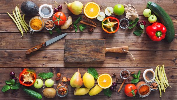 Terveellinen ruoka, puhdas ruokavalikoima: hedelmät, vihannekset, siemenet, mausteet ruskeilla laudalla, vapaa tila keskellä
 - Valokuva, kuva