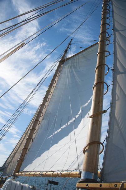Volledige zeilen slagzij uit wind de houten schoener zeilboot leunend op een zomerdag in Maine. Houten masten beveiligd door lijnen te vangen wind in de zeilen. - Foto, afbeelding