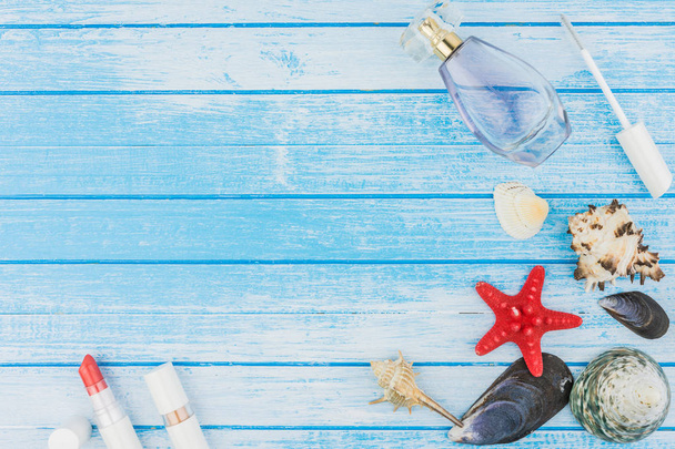 Muscheln Dekorationen Parfümflasche Lippenstift und Seestern auf blau und weiß lackiertem Holz Hintergrund hoher Kontrast Sommer Konzept Top-Winkel - Foto, Bild