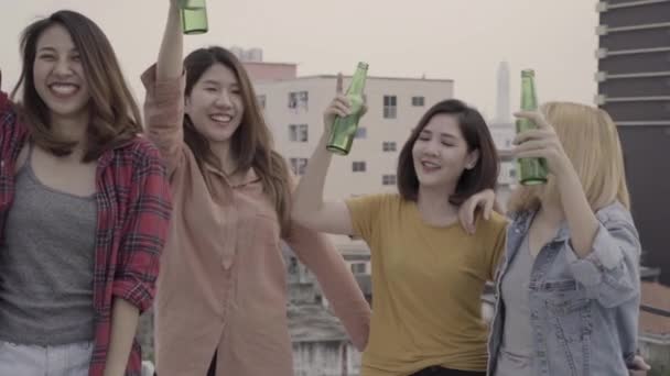 Slow motion - Group young asian women people dancing and raising their arms up in air to music played by dj at sunset urban party on rooftop. Young asian girls friends hanging out with drinks beer. - Footage, Video