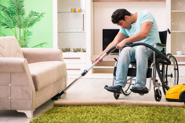 Disabled man on wheelchair vacuum cleaning house - Foto, Imagem