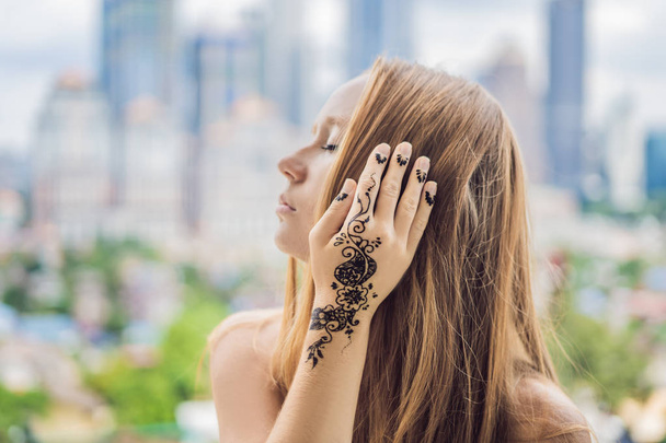 Portrait of a young Indian woman in casual style with mehendi against the background of a big city at Malaysia - Valokuva, kuva