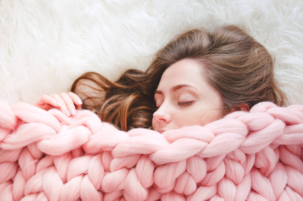 Young woman with long brown hair sleeping under warm knitted peach color throw blanket - Photo, Image