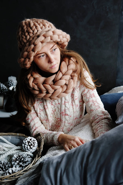 冬のファッション小物。若い女性を着たベージュ スヌード、帽子、ミトンのクリスマス ライトを眺めの寒さ. - 写真・画像