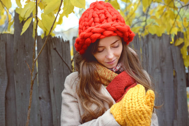 Színes őszi táj. Fiatal nő sárga ujjatlan séta a vidéken outdoorin, bézs gyapjú kabát és nagy piros térdzokni. - Fotó, kép