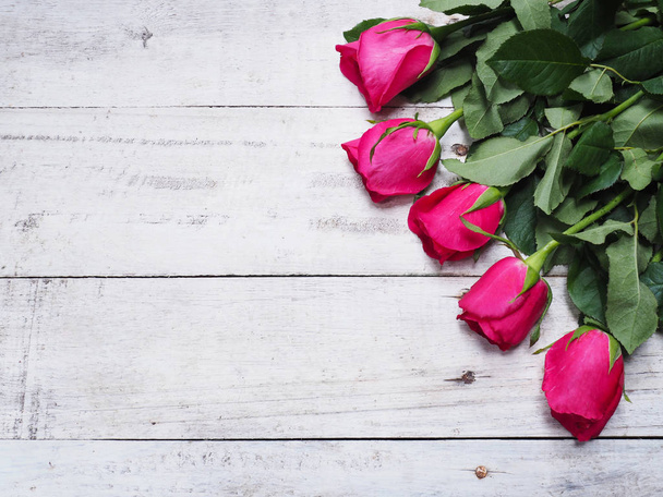 Ravvicinare rose rosse con gronda verde su sfondo in legno bianco vintage e copiare lo spazio per lo sfondo di San Valentino. Vista dall'alto
. - Foto, immagini