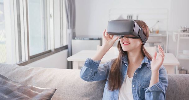woman sitting  on sofa and wearing  virtual reality headset happily - Photo, Image