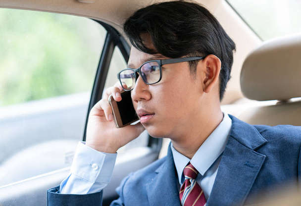 Giovani uomini d'affari asiatici ritratto in tuta parlando al telefono in auto
 - Foto, immagini
